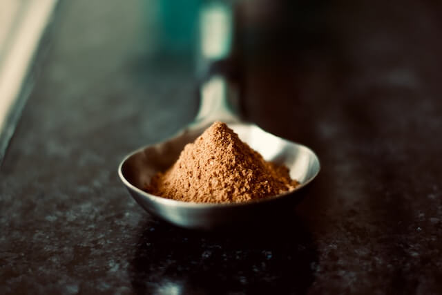 A spoon full of brown powder

Description automatically generated
