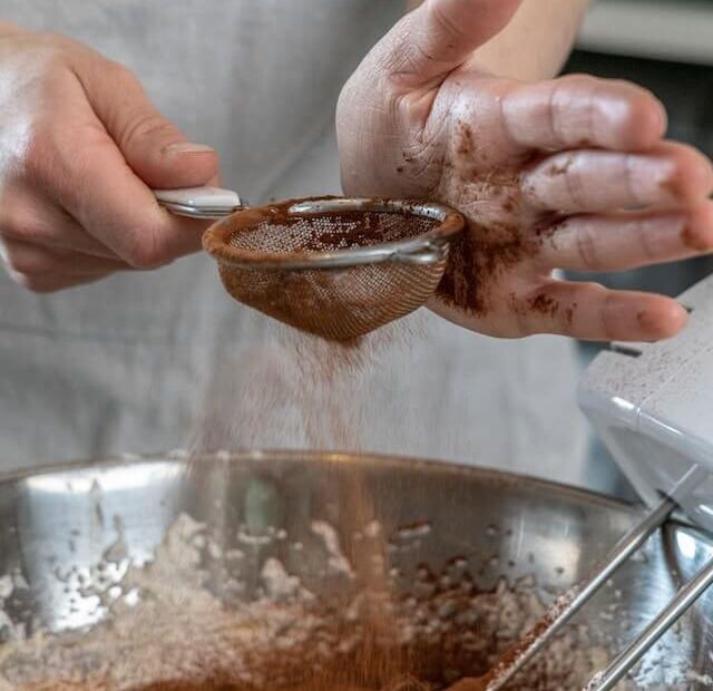 A person sifting brown powder into a bowl Description automatically generated