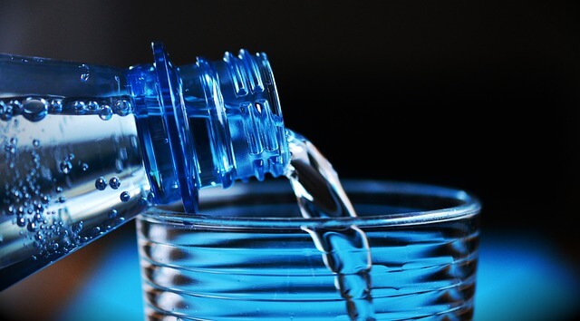 A close-up of a bottle pouring water into a glass

Description automatically generated