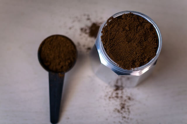 A spoon and a container of coffeeDescription automatically generated