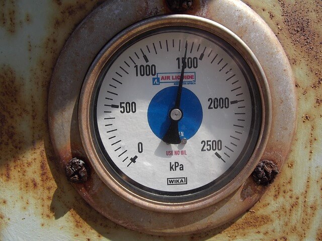 Close-up of a gauge on a rusty surfaceDescription automatically generated