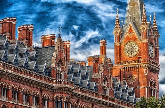 A large brick building with a clock on top with St Pancras railway station in the background

Description automatically generated
