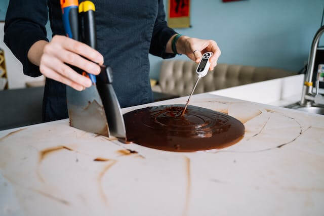 A person using a knife to cut a chocolate cakeDescription automatically generated