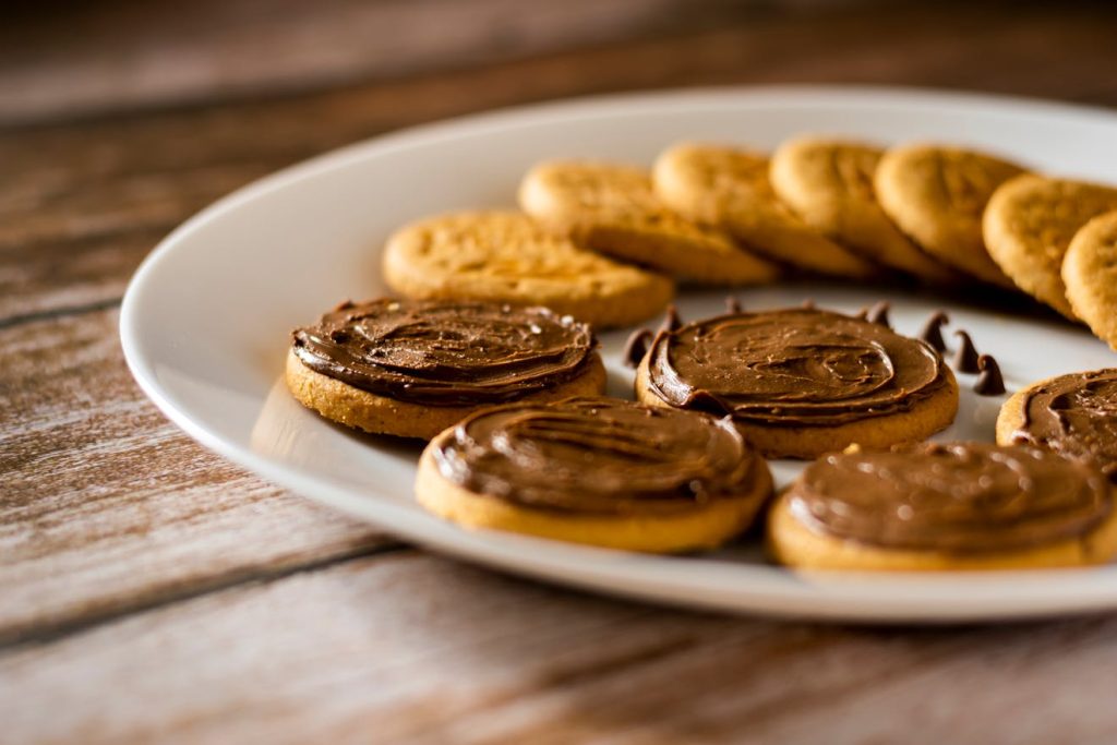 Delicious biscuits topped with rich chocolate spread on a rustic wooden surface.