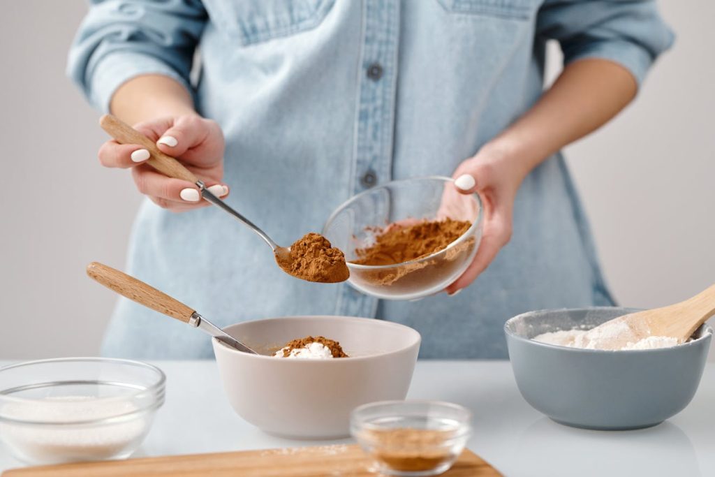 Close-up of hands measuring cocoa powder for home baking preparation.