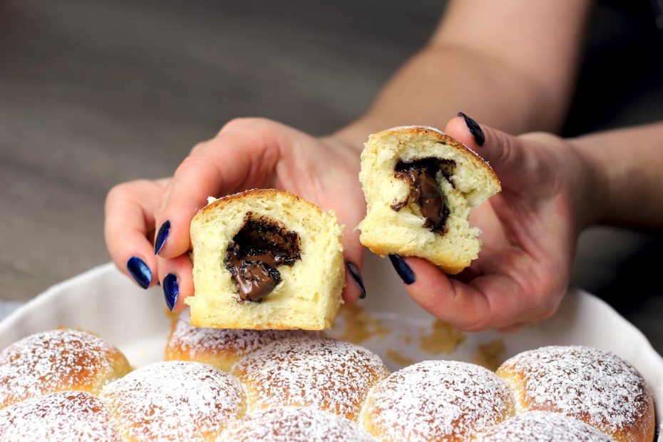Close-up of a chocolate-filled pastry being split open, showcasing gooey filling.
