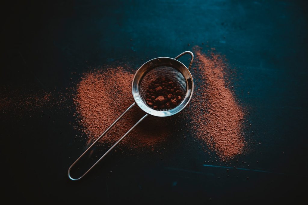 round grey metal filter with brown powder on black surface