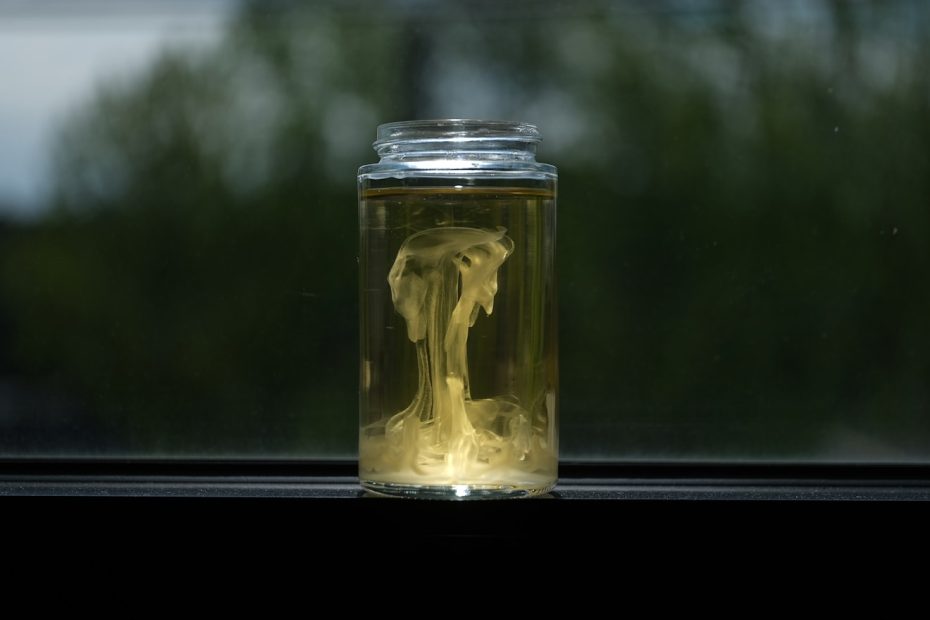 Yellow smoke swirls inside a glass jar.